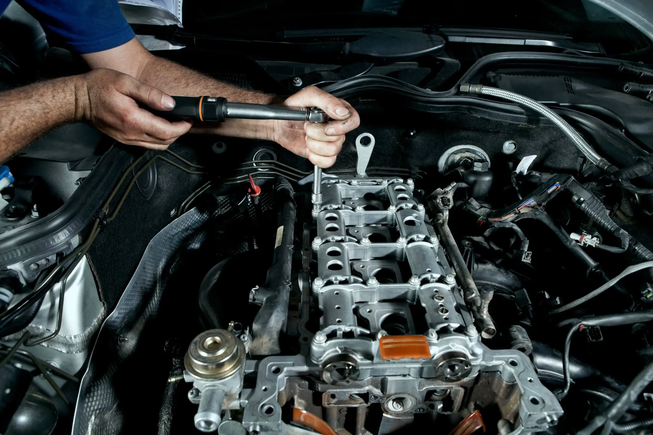Mechanic working on car engine assembly.