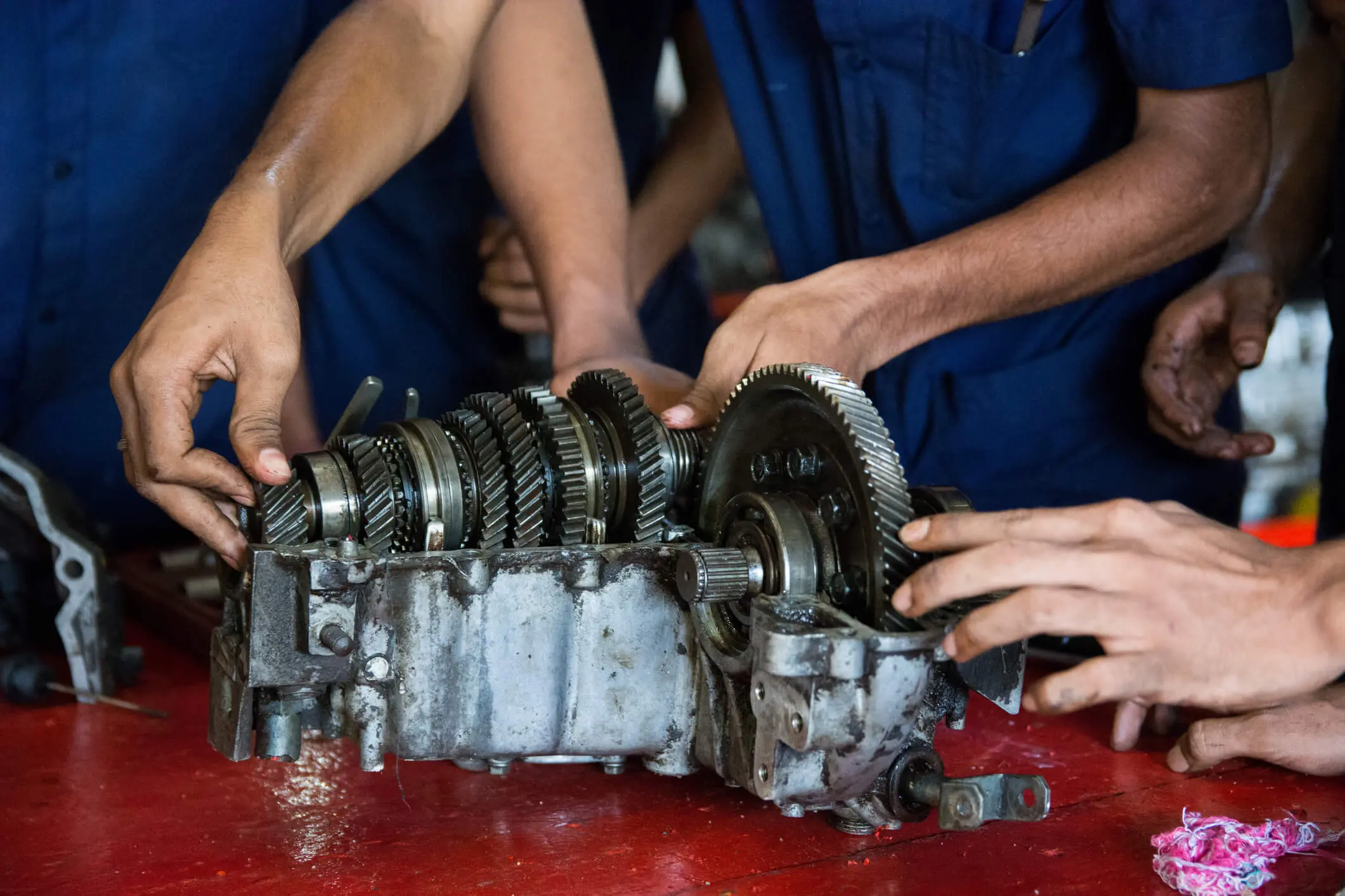Hands working on a mechanical gearbox assembly.