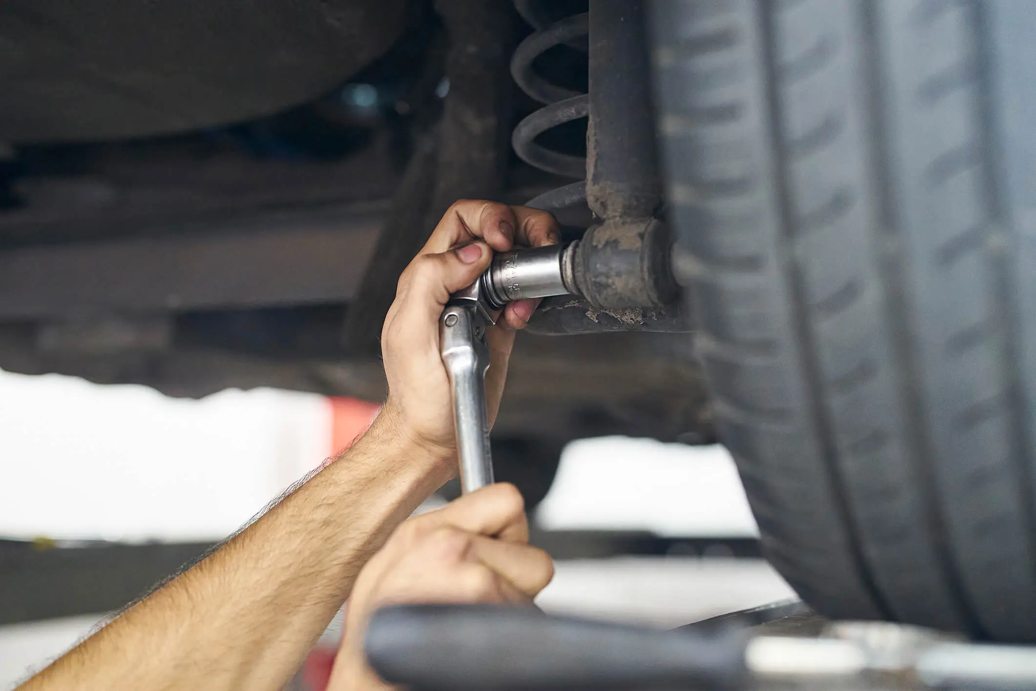 Mechanic using wrench on car suspension.