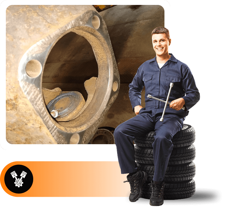 Mechanic sitting on tires, holding tools.